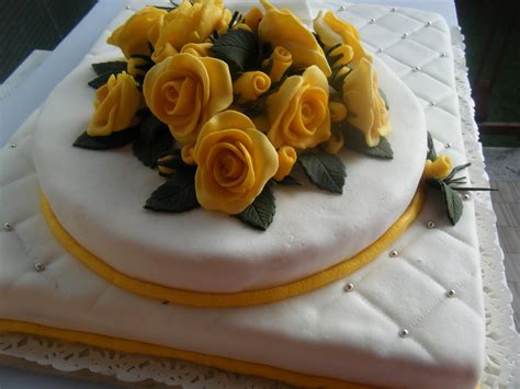 Torta nuziale decorata con rose gialle e dettagli dorati